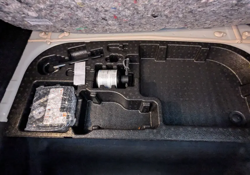 Rangement sous le plancher de coffre de l'Alpine A290 blanc toit noir, montrant les outils et accessoires intégrés.