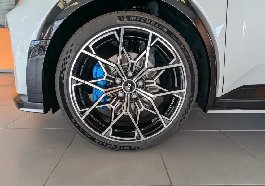 Gros plan sur la jante avant droite noire diamantée 19 pouces de l'Alpine A290 blanc toit noir avec étrier de frein bleu.