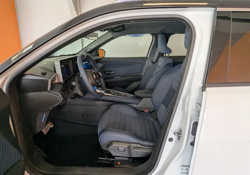 Vue intérieure côté conducteur de l'Alpine A290 220CH GT PERFORMANCE 2026 blanc toit noir avec sièges bleu marine et tableau de bord moderne.