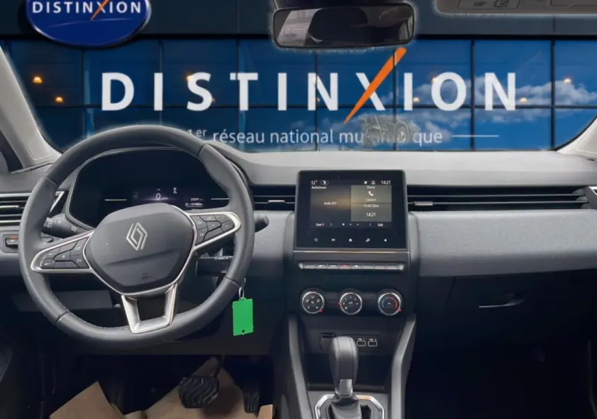 Vue intérieure avant du tableau de bord et volant noir de la Renault Clio V blanche avec écran tactile et commandes au volant.