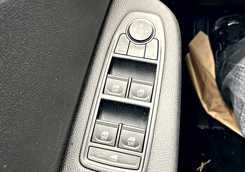 Gros plan sur les commandes de lève-vitres électriques côté conducteur d'une Renault Clio V blanche, finition 2025.