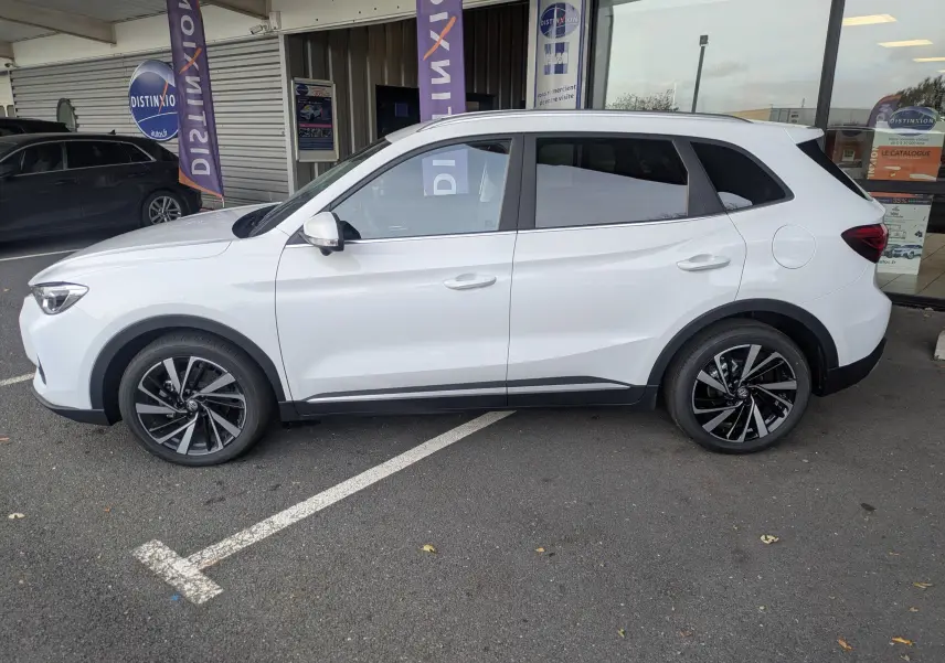 Vue de profil côté gauche d'un MG ZS blanc 2026 avec jantes alliage 18 pouces et toit panoramique.