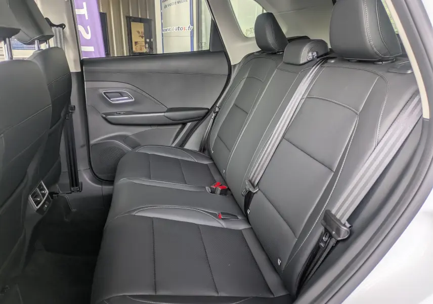 Vue latérale droite de l'intérieur arrière du MG ZS 2026 blanc, sièges noirs en similicuir perforé avec ceintures grises.
