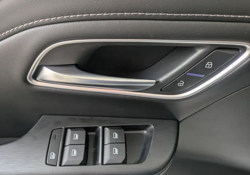 Gros plan sur la poignée intérieure et les commandes de fenêtre côté conducteur du MG ZS blanc 2026.