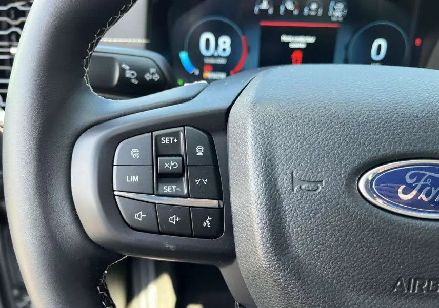 Gros plan sur le volant multifonctions noir du Ford Ranger 2026 avec commandes de régulateur et logo Ford visible.
