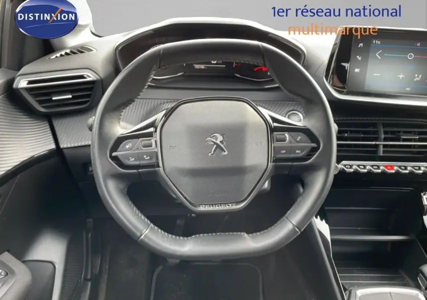 Vue intérieure centrée sur le volant Peugeot d'une 208 rouge Elixir 2022, avec tableau de bord et écran tactile visibles.