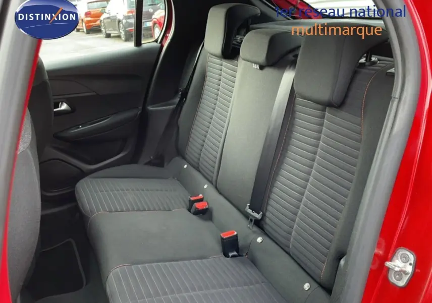 Vue intérieure côté gauche des sièges arrière noirs avec surpiqûres orange d'une Peugeot 208 rouge Elixir 2022.