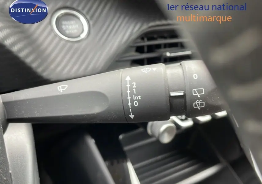 Gros plan sur la commande d’essuie-glace à gauche du volant dans l’habitacle d’une Peugeot 208 rouge Elixir Metal.