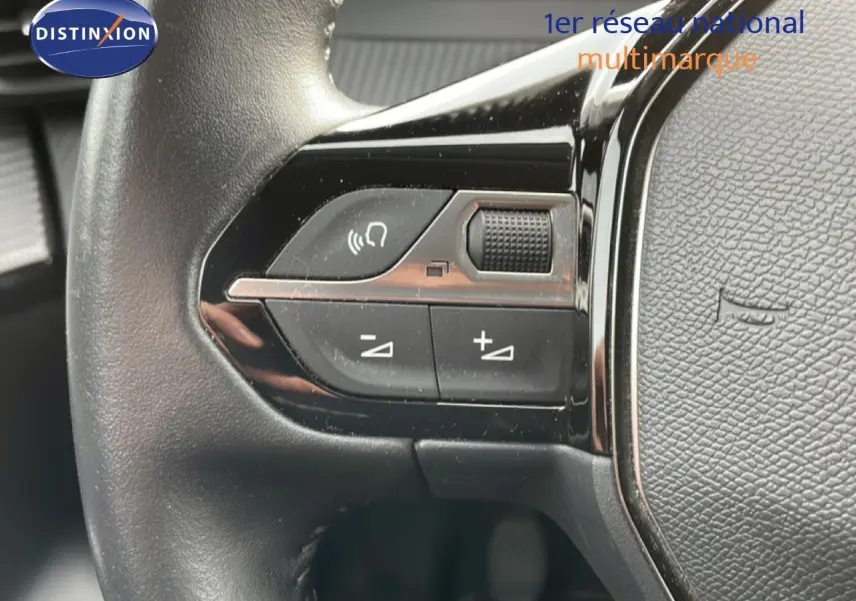 Détail du volant avec commandes audio sur la gauche d'une Peugeot 208 rouge Elixir Metal, version 2022.