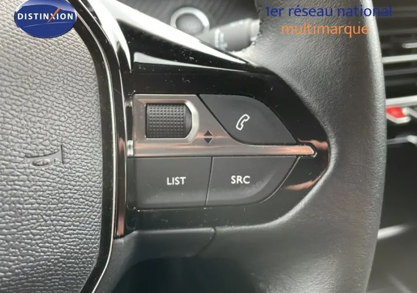Gros plan sur les commandes gauche du volant en cuir noir de la Peugeot 208, boutons pour appels et audio.
