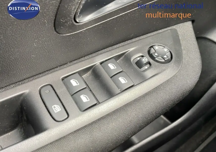 Gros plan sur les commandes de lève-vitres et rétroviseurs côté conducteur d'une Peugeot 208 1.5 BlueHDi rouge Elixir.
