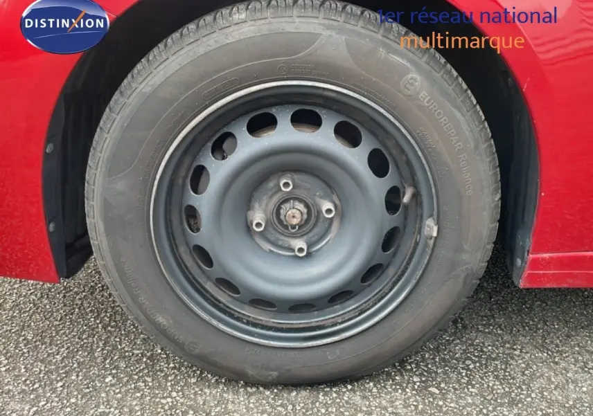 Gros plan sur la roue avant droite en jante acier d'une Peugeot 208 rouge Elixir Metal, version diesel 2022.