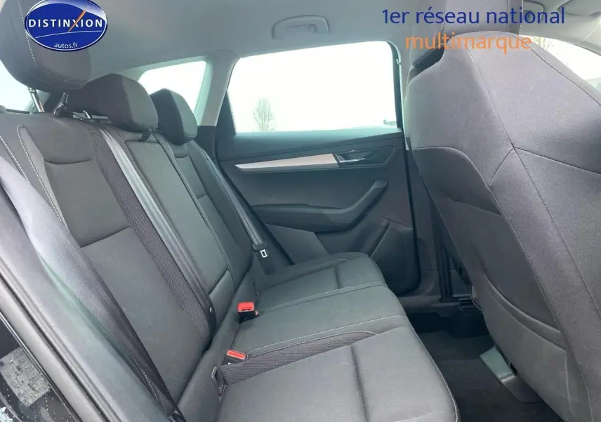 Intérieur arrière du Skoda Karoq 2025 en tissu noir, vue côté gauche avec banquette 3 places et ceintures visibles.