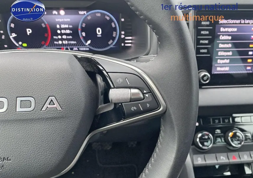 Gros plan sur le volant cuir multifonction noir d’un Skoda Karoq 1.5 TSI 2025 avec tableau de bord digital et écran tactile.