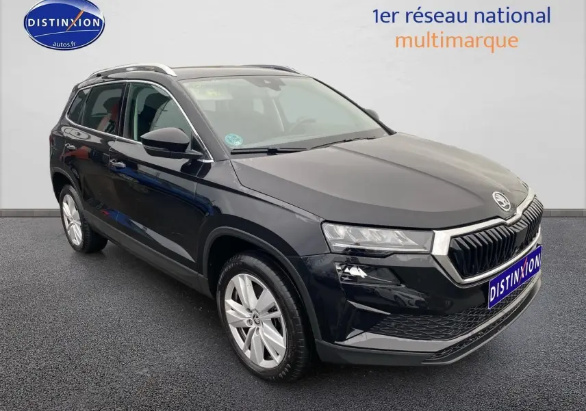 Vue 3/4 avant droit d'un Skoda Karoq noir 2025 avec jantes alu et barres de toit visibles.