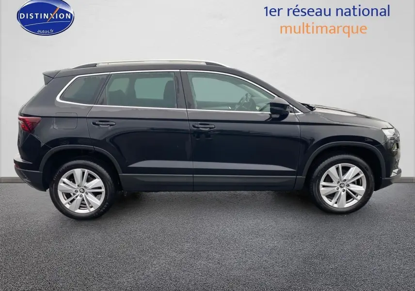 Profil côté droit du SUV SKODA KAROQ noir 2025 avec jantes alu et barres de toit visibles sur fond neutre.