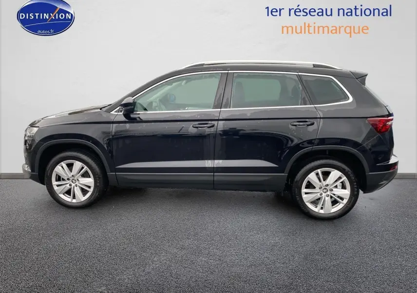 Vue de profil côté gauche d'un Skoda Karoq noir 2025 avec jantes alu et barres de toit visibles.