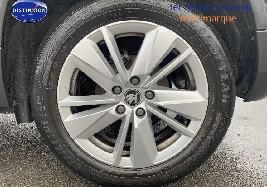 Gros plan sur la jante alu argentée avec logo SKODA d'un SUV noir, vue côté droit, pneu Goodyear visible.