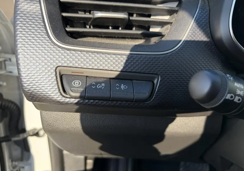 Détail du tableau de bord noir texturé avec commandes d’éclairage et ventilation du Renault Arkana blanc glacier 2025.