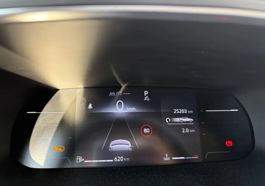 Tableau de bord numérique du Renault Arkana 2025 affichant vitesse, autonomie et alertes, vue frontale rapprochée.