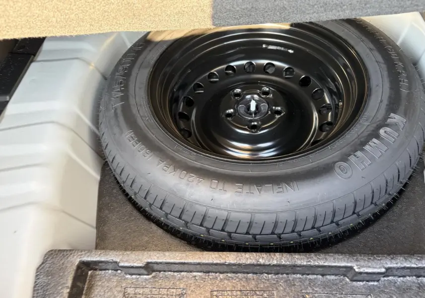 Vue rapprochée de la roue de secours noire dans le coffre d’un Renault Arkana Blanc Glacier 2025.