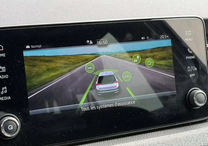 Écran tactile intérieur affichant l'aide à la conduite avec vue arrière stylisée d'une Skoda Scala blanche sur route.