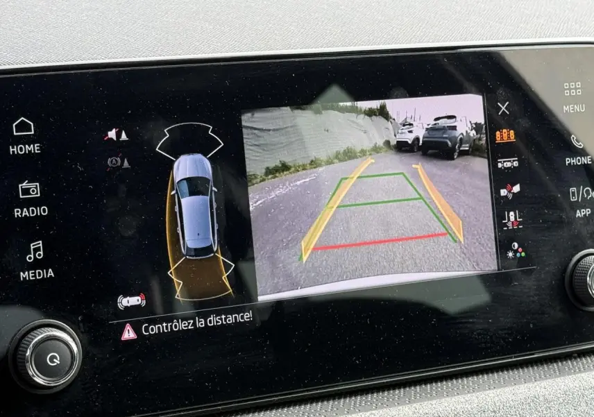 Écran tactile intérieur montrant la caméra de recul active d'une Skoda Scala blanche Glacier en stationnement.