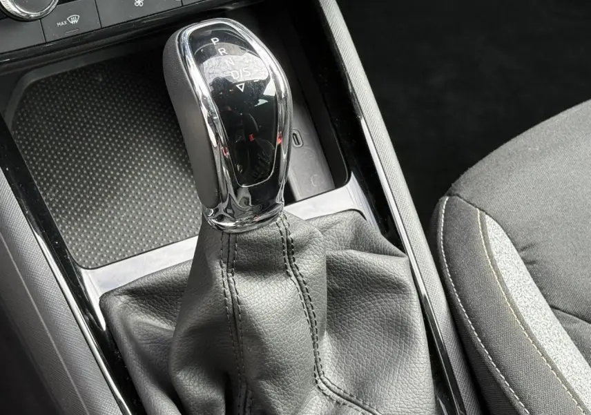 Le levier de vitesses automatique chromé et noir de la Skoda Scala TSI 116 DSG7, avec console et siège tissu gris.