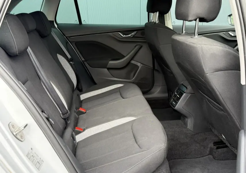 Vue intérieure arrière côté gauche de la Skoda Scala TSI 116 DSG7 blanche, sièges tissu gris avec surpiqûres claires.