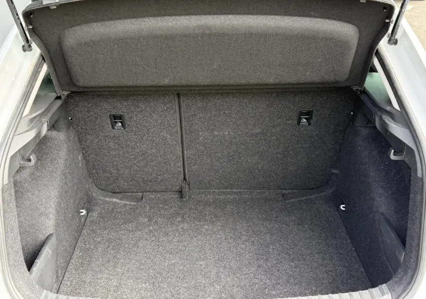 Coffre ouvert de la Skoda Scala blanc Glacier, vue intérieure montrant un espace de chargement propre et spacieux.