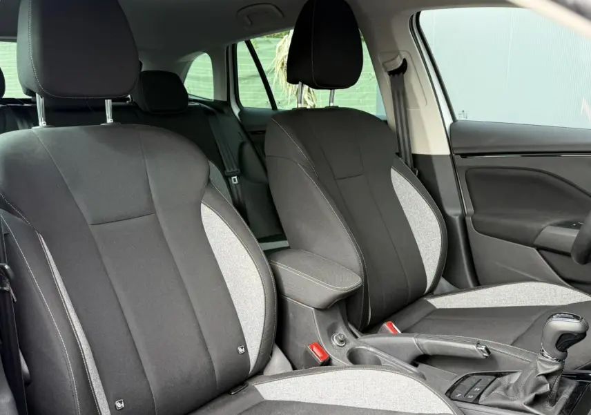 Intérieur de la Skoda Scala TSI 116 DSG7 blanc Glacier, vue rapprochée des sièges avant bicolores noirs et gris.