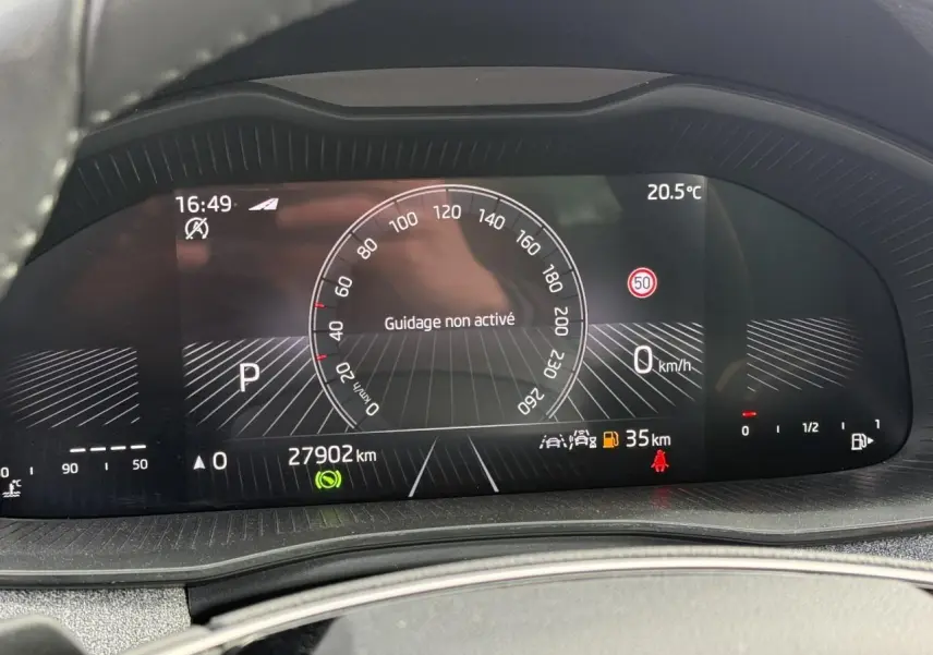 Tableau de bord numérique de la Skoda Scala blanc glacier, affichant la vitesse à 0 km/h et 27 902 km au compteur.