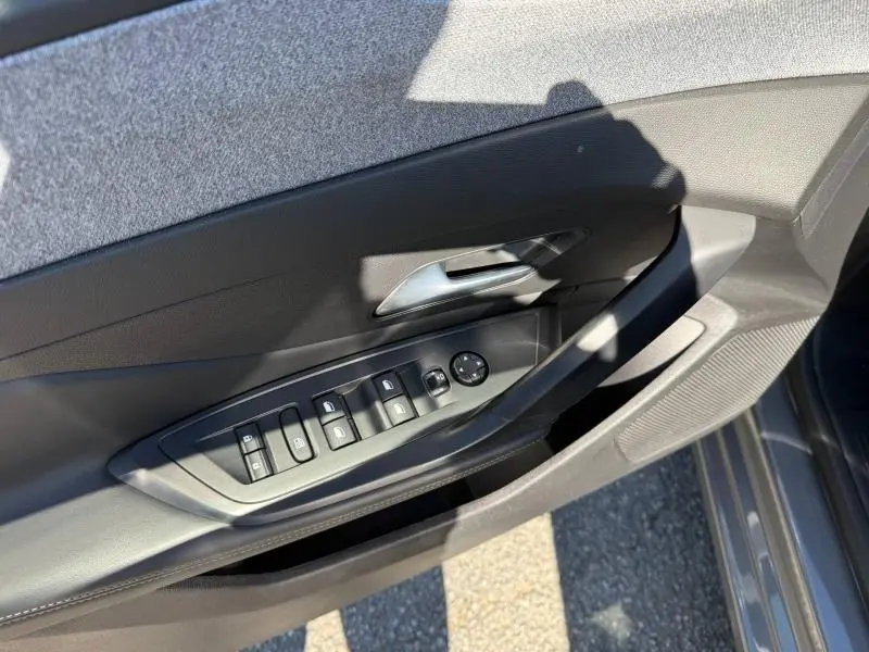 Vue rapprochée de la porte côté conducteur du Peugeot 308 gris 2025, avec commandes des vitres et rétroviseurs.
