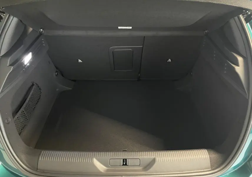 Coffre ouvert de la Peugeot 308 Bleu Lagoa, vue arrière montrant l'espace de rangement vide et l'éclairage intérieur.