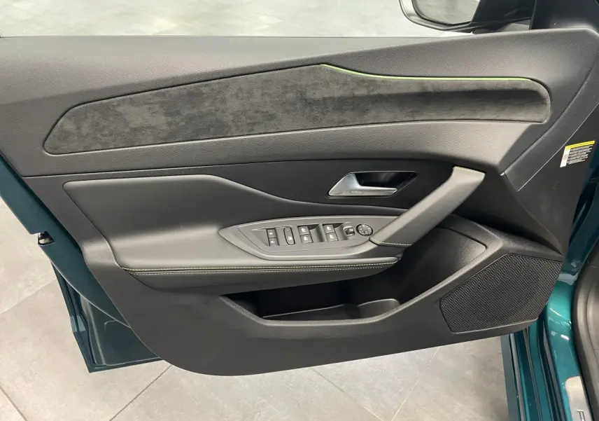 Vue intérieure côté gauche de la porte avant bleu métallisé avec garniture noire et surpiqûres vert Adamite sur Peugeot 308 2026.