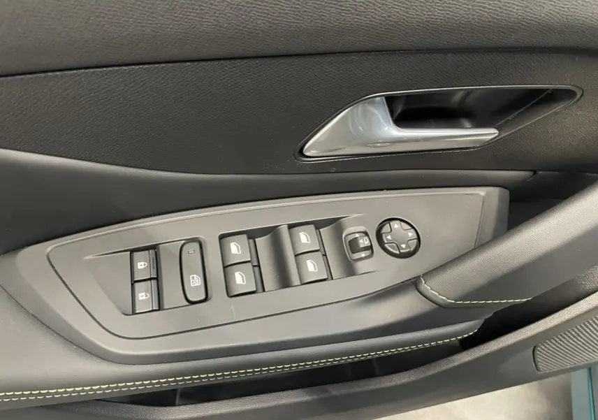 Gros plan sur la commande des vitres et rétroviseurs côté conducteur de la Peugeot 308 GT bleu avec surpiqûres vert Adamite.