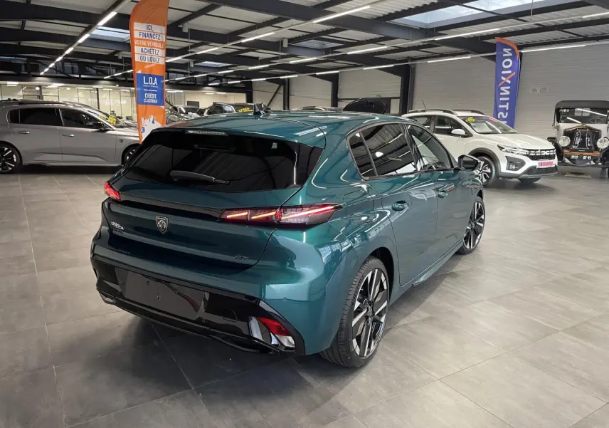 Vue 3/4 arrière droite d'une Peugeot 308 GT bleu métallisé avec jantes alliage bi-tons et feux arrière LED 3 griffes.