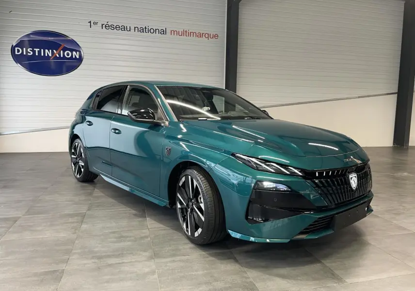 PEUGEOT 308 2026 bleu Lagoa en 3/4 avant droit avec calandre noire et jantes alliage bi-tons visibles en intérieur showroom.