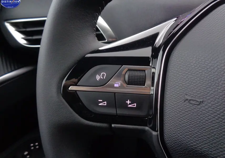Gros plan sur les commandes du volant à gauche du Peugeot 3008 gris Artense 2023, avec boutons de volume et reconnaissance vocale.