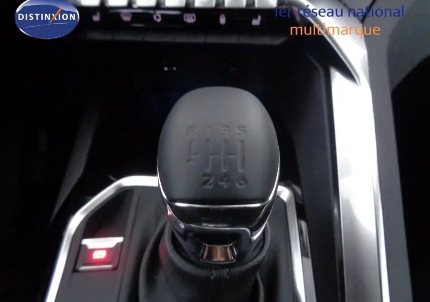 Gros plan sur le levier de vitesses manuel noir du Peugeot 3008 gris Artense, avec éclairage rouge du frein à main électronique.