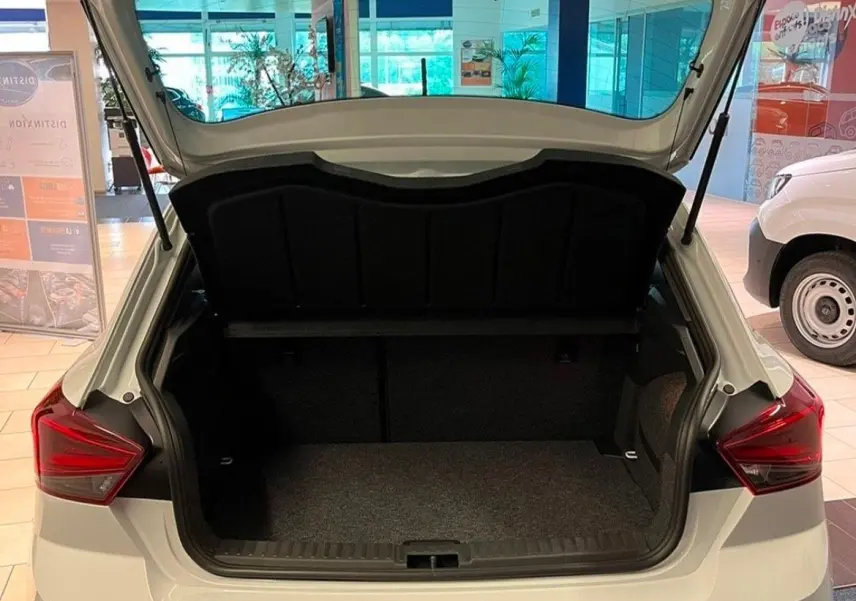 Vue arrière d'une SEAT Ibiza blanche Nevada Metal 2024 avec coffre ouvert et feux arrière LED visibles en showroom.
