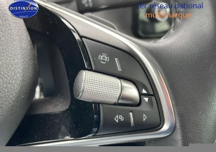 Gros plan sur les commandes multifonctions en métal et plastique noir du volant cuir d’un Skoda Kamiq gris.