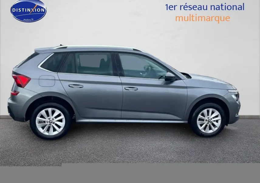 Vue latérale droite d'un Skoda Kamiq gris 2025 avec jantes alliage et barres de toit visibles.