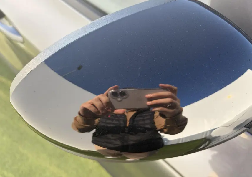 Gros plan sur le rétroviseur droit gris métallisé du Renault Arkana 2025 avec reflet d'une personne prenant la photo.