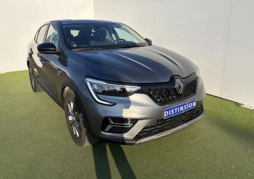 Renault Arkana gris métallisé vu en 3/4 avant droit, mettant en valeur ses phares LED et sa calandre noire.