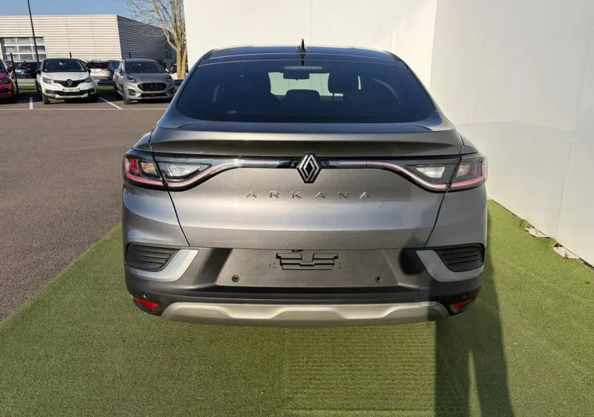 Vue arrière d’un Renault Arkana gris métallisé avec feux LED reliés et logo centré sur un parking.