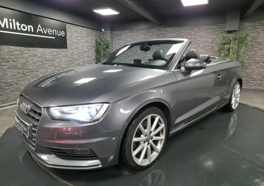 Audi A3 Cabriolet gris métallisé vue 3/4 avant droit avec capote ouverte et jantes sport 18 pouces.