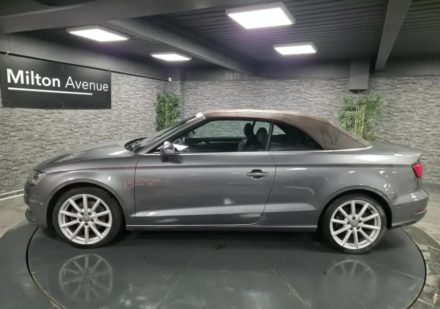 Profil côté gauche d'une Audi A3 Cabriolet gris métallisé avec capote fermée marron, jantes 18 pouces en aluminium.