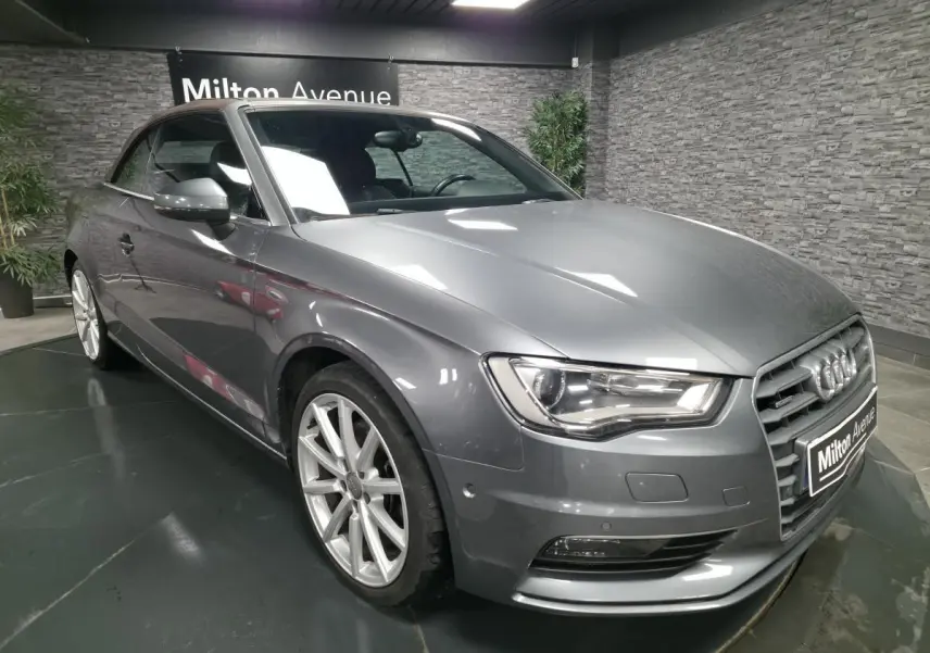 Audi A3 Cabriolet gris en 3/4 avant droit, capote fermée, jantes aluminium 18 pouces et calandre Singleframe chromée.