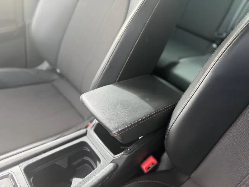 Vue rapprochée de l’accoudoir central noir en cuir avec surpiqûres contrastantes dans l’habitacle du CUPRA Formentor bleu.